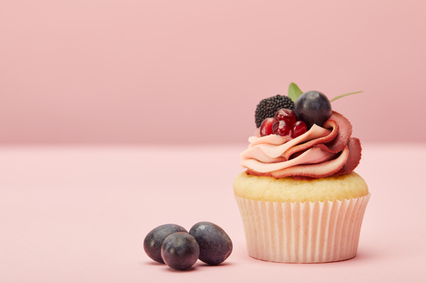 sweet cupcake with cream and grapes on pink surface - Фото, зображення
