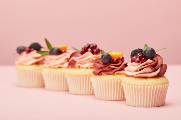 ピンクの表面に果物やベリーと甘いカップケーキ - 写真・画像
