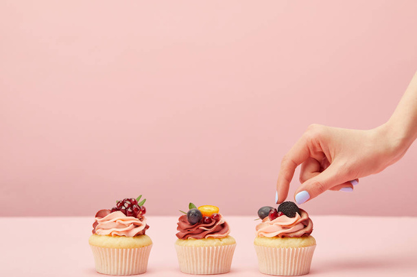cropped view of woman with sweet cupcakes with fruits and berries isolated on pink - Fotoğraf, Görsel