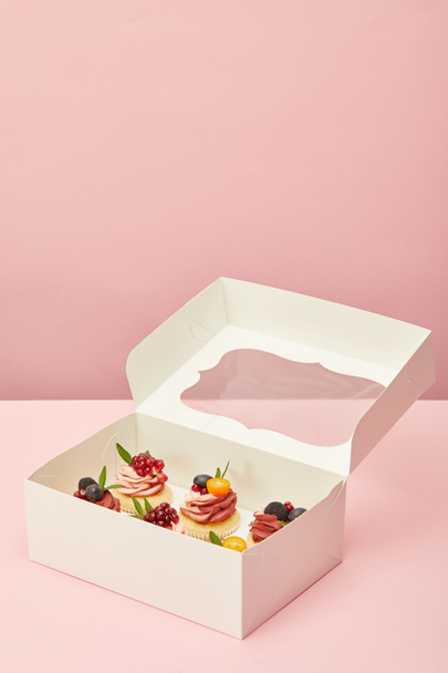 λευκό κουτί με γλυκά cupcakes σε ροζ επιφάνεια - Φωτογραφία, εικόνα