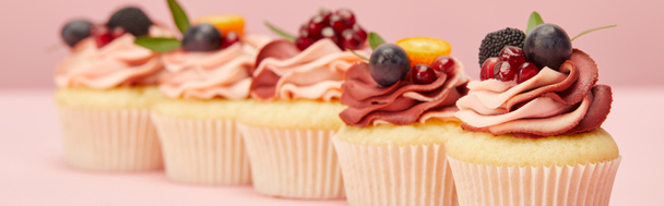 panoramic shot of sweet cupcakes with berries and fruits on pink surface - Fotó, kép