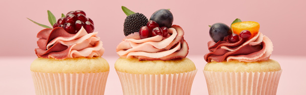 panoramic shot of sweet cupcakes with berries and fruits on pink surface - Foto, Imagen