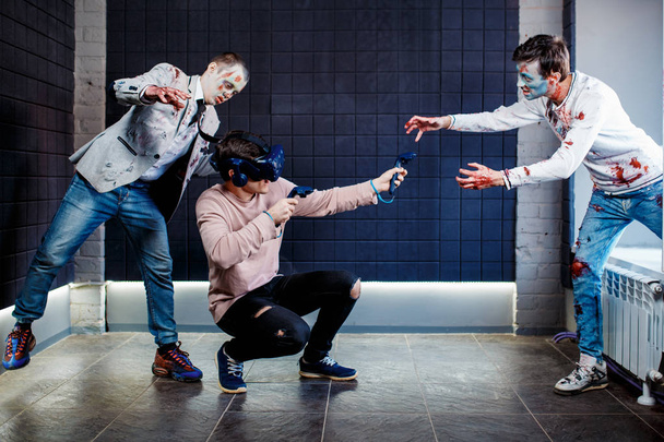 Concept, a man playing video games about zombies, wearing virtual reality glasses. Grim zombies. - Valokuva, kuva