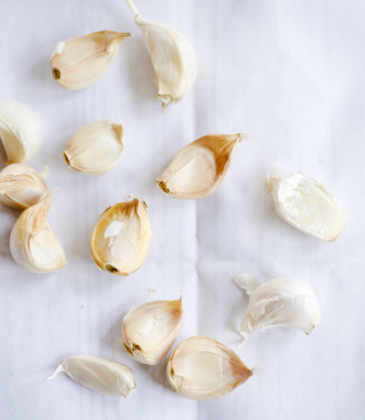 garlic cloves and peels on white tablecloth - Fotoğraf, Görsel