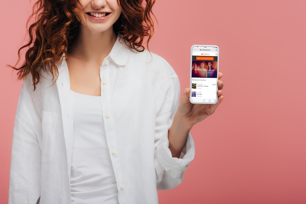 cropped view of cheerful girl holding smartphone with soundcloud app on screen on pink - Foto, imagen