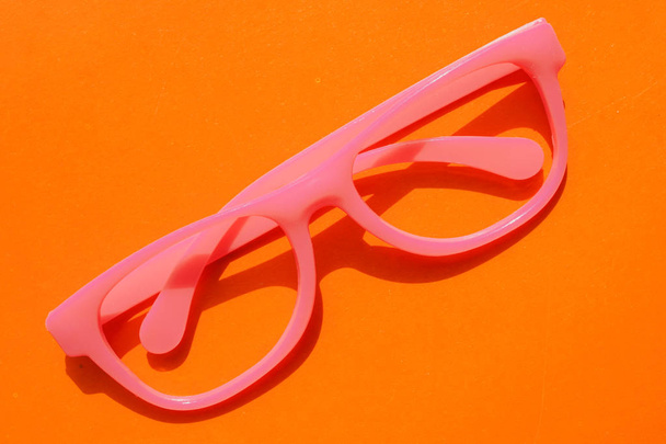 Las gafas de plástico rosa se encuentran sobre fondo naranja. concepto de hipsters divertidos
. - Foto, imagen