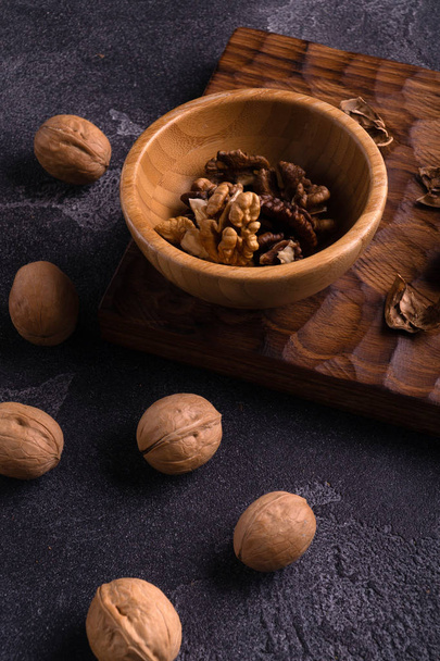 Walnuts in wooden bowl and on blue slate table. Healthy nuts and seeds composition. - Foto, Imagem