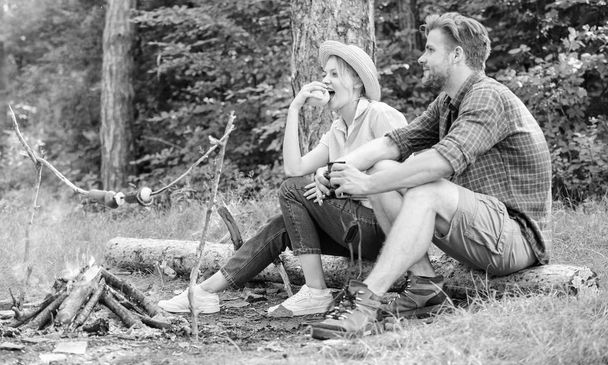Couple romantic date near bonfire in forest. Couple relaxing sit on log having snacks. Pleasant picnic or romantic date nature background. Hike picnic date. Family enjoy romantic weekend in nature - Photo, Image