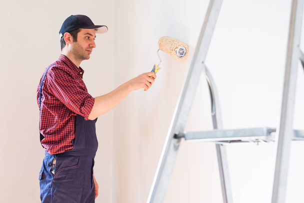 Ремонт, ремонт и концепция дома с человеком покраски стены в доме
 - Фото, изображение