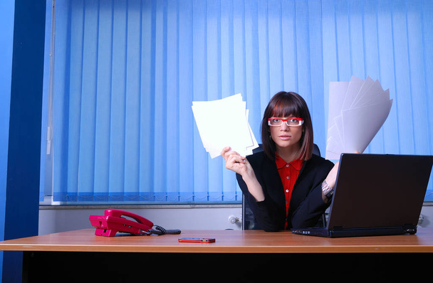 young businesswoman holding papers at workplace - Fotó, kép