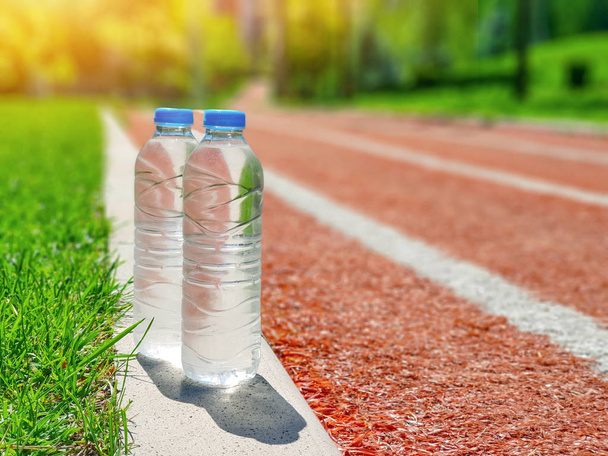 cold water bottles near synthetic tartan track  - Photo, Image