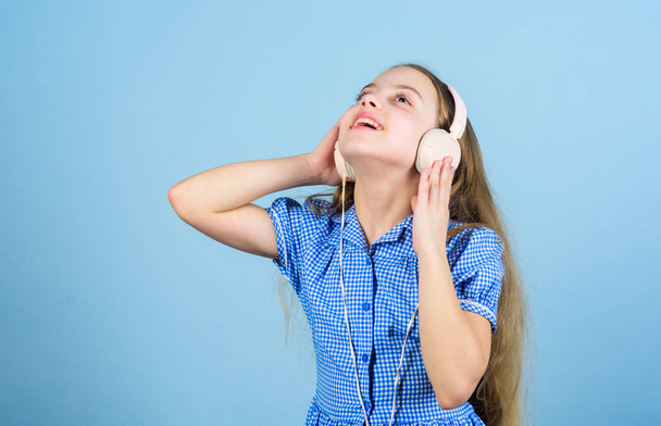 Inspired by music. Little kid listening music. Cute kid with headphones blue background. Small girl wearing stereo headphones. Child using technology for leisure or education. Modern headphones - Фото, зображення