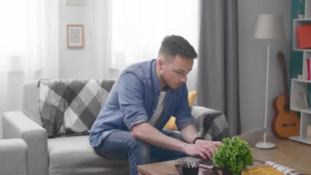 Man sitting on sofa and finish working on laptop computer - Filmmaterial, Video