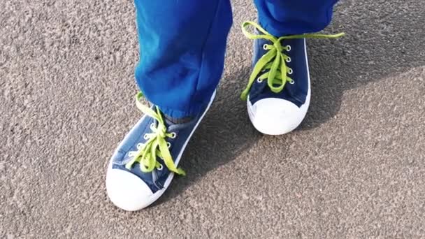nogi małego dziecka w tenisówki na asfalcie - Materiał filmowy, wideo