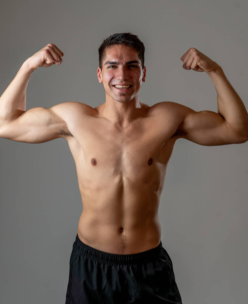 Portrait of strong handsome Athletic man isolated on neutral background. Mixed race latin fitness model posing showing biceps and strong body. In exercise, healthy lifestyle, workout and body care. - Foto, immagini