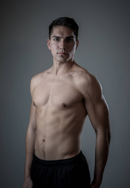 Strong handsome Athletic young man isolated on neutral background. Mixed race latin muscly model posing for fitness marketing advertising. In exercise, healthy lifestyle, workout and body care. - 写真・画像
