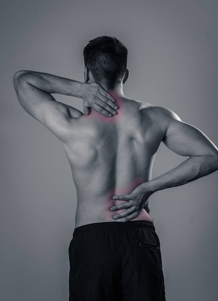 Young muscular fitness man touching and grabbing his neck and lower back suffering cervical pain isolated on neutral background. In sport and workout injury, Incorrect posture problems and body care. - Fotografie, Obrázek