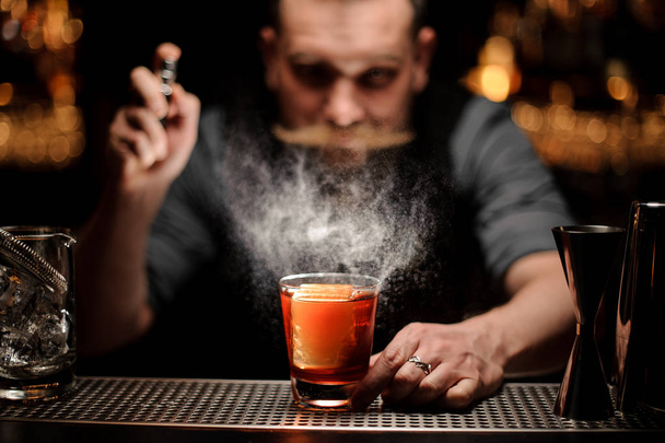 Brutal bartender pours an alcohol cocktail using sprayer - Foto, Bild