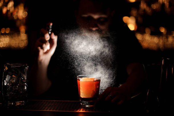 Darkened close shot of bartender pouring cocktail using sprayer - Фото, изображение