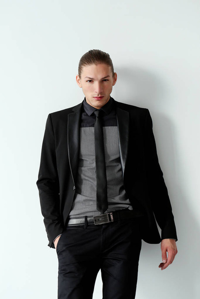 Portrait of a handsome man in a black suit who is posing over a white background - Photo, Image