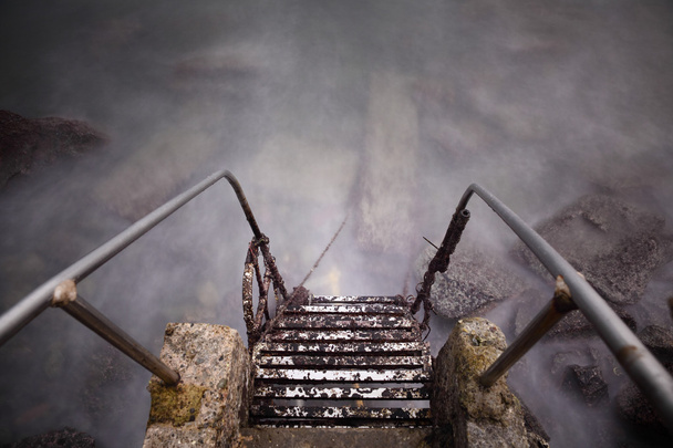 staal en stenen oude ladder naar zee - Foto, afbeelding
