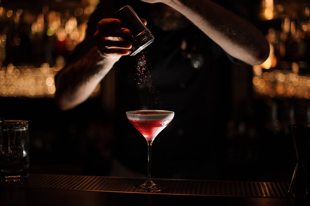 Bartender sprinkles the alcohol cocktail in glass - 写真・画像
