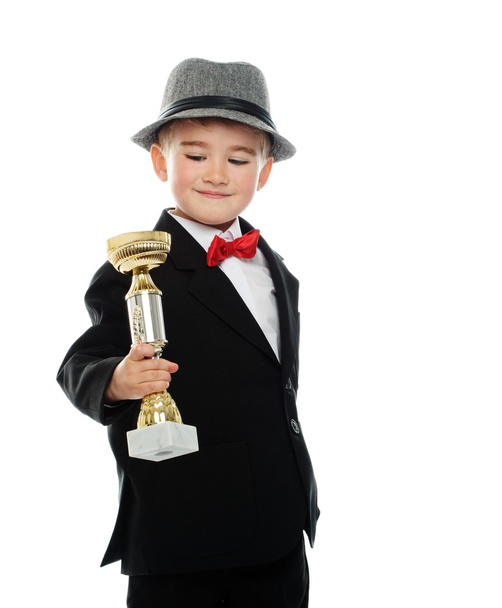 Boldog fiú fekete öltöny kezében díj kupa - Fotó, kép