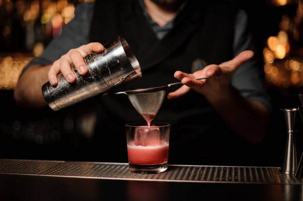 Close shot of bartender making cocktail with shaker and sieve - Fotó, kép