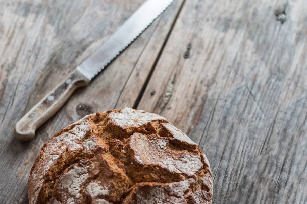 Fresh, crispy bread on rustic wooden cutting board. Outdoors.  - Фото, зображення