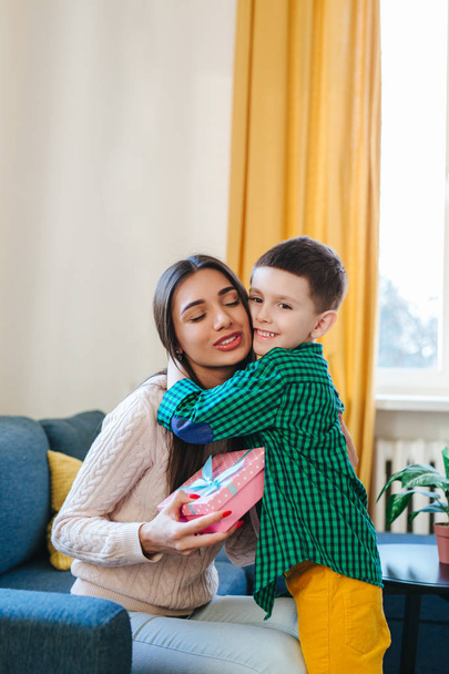 Happy mother hugging her adorable little son and holding gift box. Mothers Day - Foto, Imagem