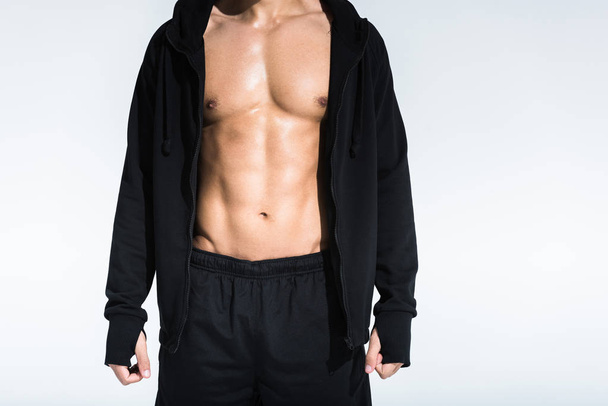 cropped view of sportive man with muscular torso in black sportswear on white background - Фото, изображение