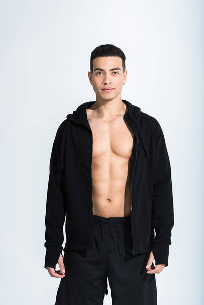 handsome mixed race man in black sportswear looking at camera on white - Foto, Bild