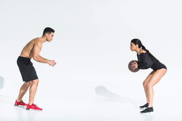 sportive multicultural young man and woman playing ball on white background - Photo, Image