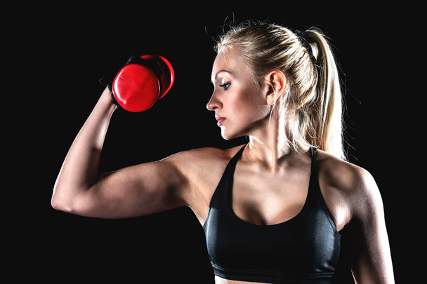 Sports girl pumps biceps with a dumbbell. - Fotografie, Obrázek