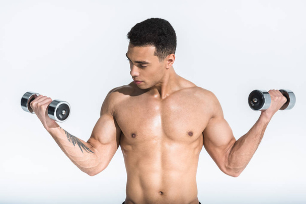 good-looking athletic mixed race man with muscular torso holding dumbbells on white - Photo, image