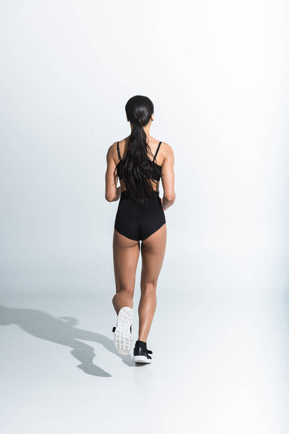 Achteraanzicht van sportieve African American Girl draait op witte achtergrond - Foto, afbeelding