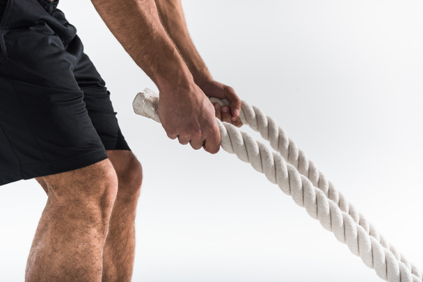 cropped view of sportive man holding white ropes on white background  - Fotografie, Obrázek