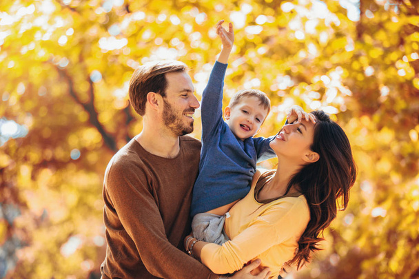 Молодая семья веселится в осеннем парке со своим сыном
. - Фото, изображение