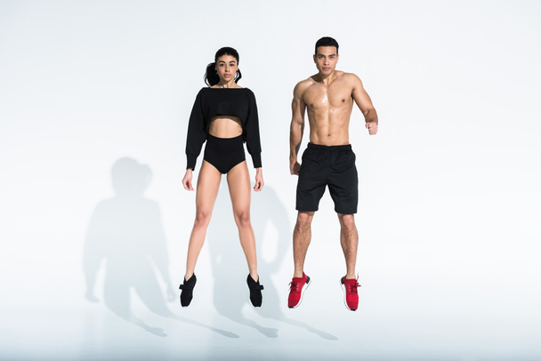 sportive multicultural man and woman jumping on white background - Foto, Bild