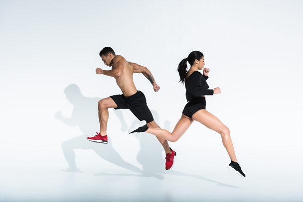 スポーティなアフリカ系アメリカ人の女の子と運動混合レースの男は白い背景に走っています - 写真・画像