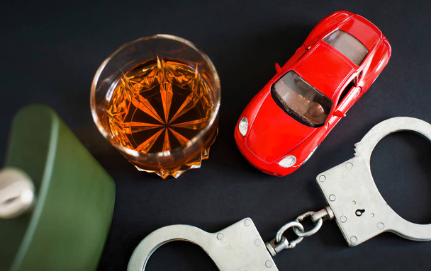 Drunk driving. Alcohol, car, handcuffs on a black background - Photo, Image
