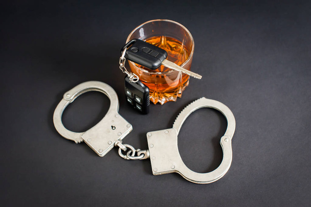 Οδήγηση μεθυσμένος. Αλκοόλ, κλειδιά αυτοκινήτου, χειροπέδες σε μαύρο φόντο - Φωτογραφία, εικόνα