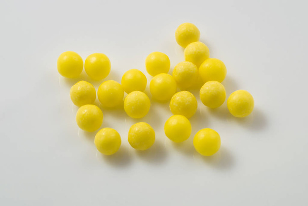 Yellow pills scattered on a white background. - Φωτογραφία, εικόνα