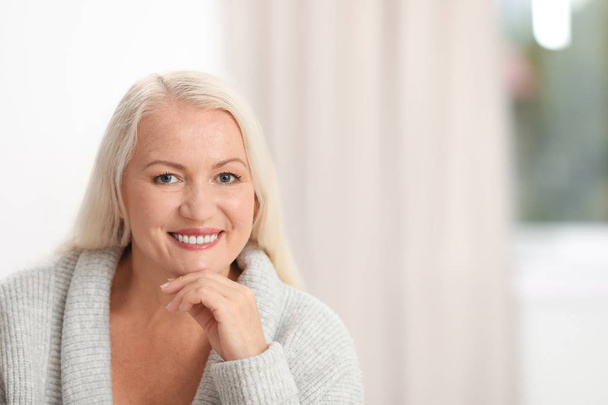 Portrait of beautiful older woman against blurred background with space for text - Valokuva, kuva
