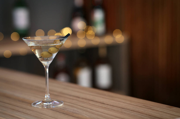 Delicious martini cocktail with olives on table in bar, space for text - 写真・画像