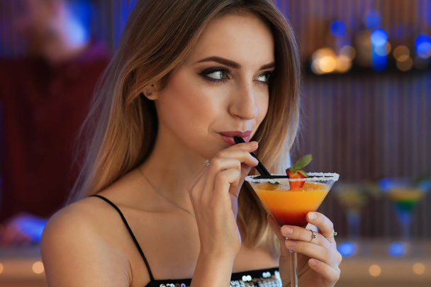 Beautiful young woman with glass of martini cocktail in bar - Fotó, kép