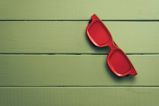 Gafas rojas sobre un fondo de mesa de madera verde. Concepto de verano
. - Foto, Imagen