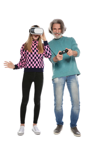 Teenage girl wearing VR headset and mature man with controller playing video games on white background - Photo, image