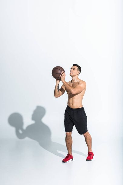 handsome sportive mixed race man playing ball on white background  - 写真・画像