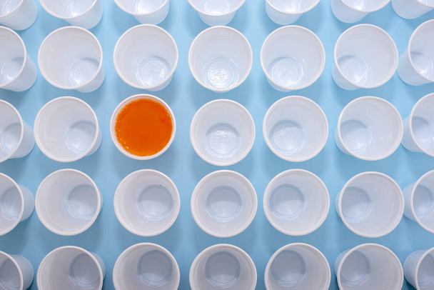 Tasses vides jetables en plastique blanc et un verre rempli de limonade orange
 - Photo, image